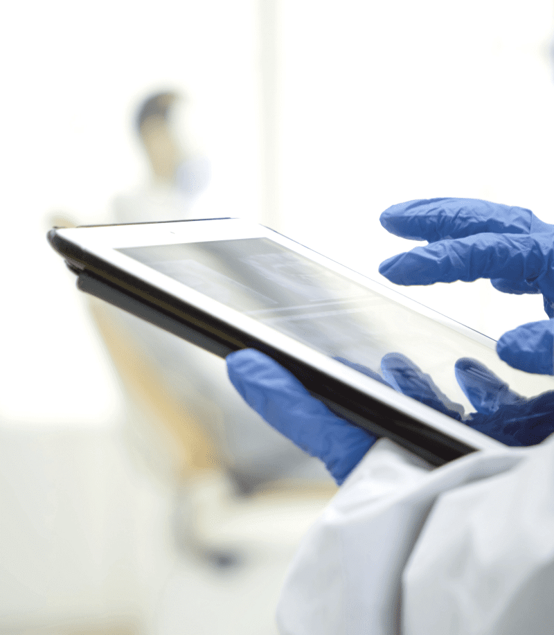 Close up of a gloved hand checking test results on a tablet.